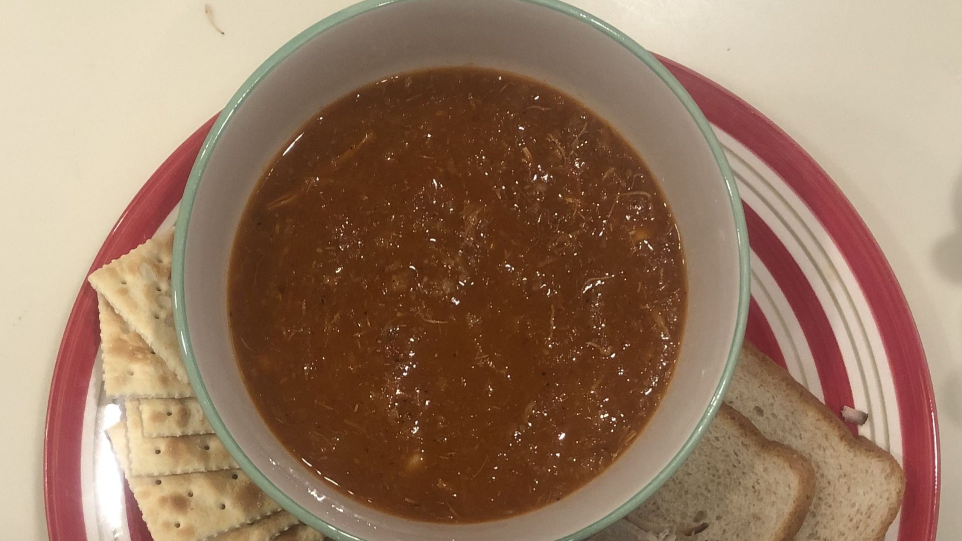 Kentucky Burgoo served with wheat bread, crackers, pulled pork, barbecue sauce, and pickle slices.