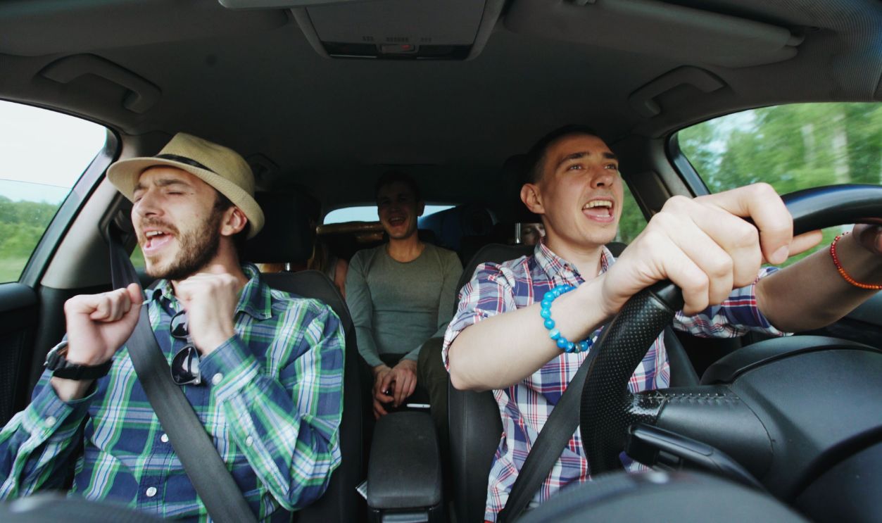 Three friends singing joyfully during a road trip
