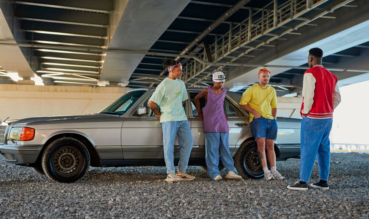 Casual group of young adults relaxing under a bridge with a vintage car