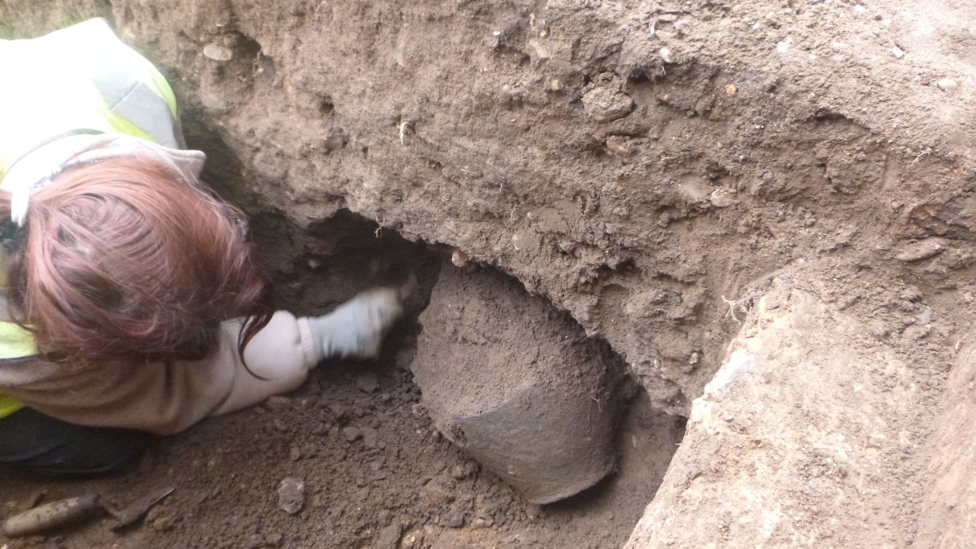 Archaeologist excavating a ceramic at 86 Lexden Road, Colchester, Essex, January 2023