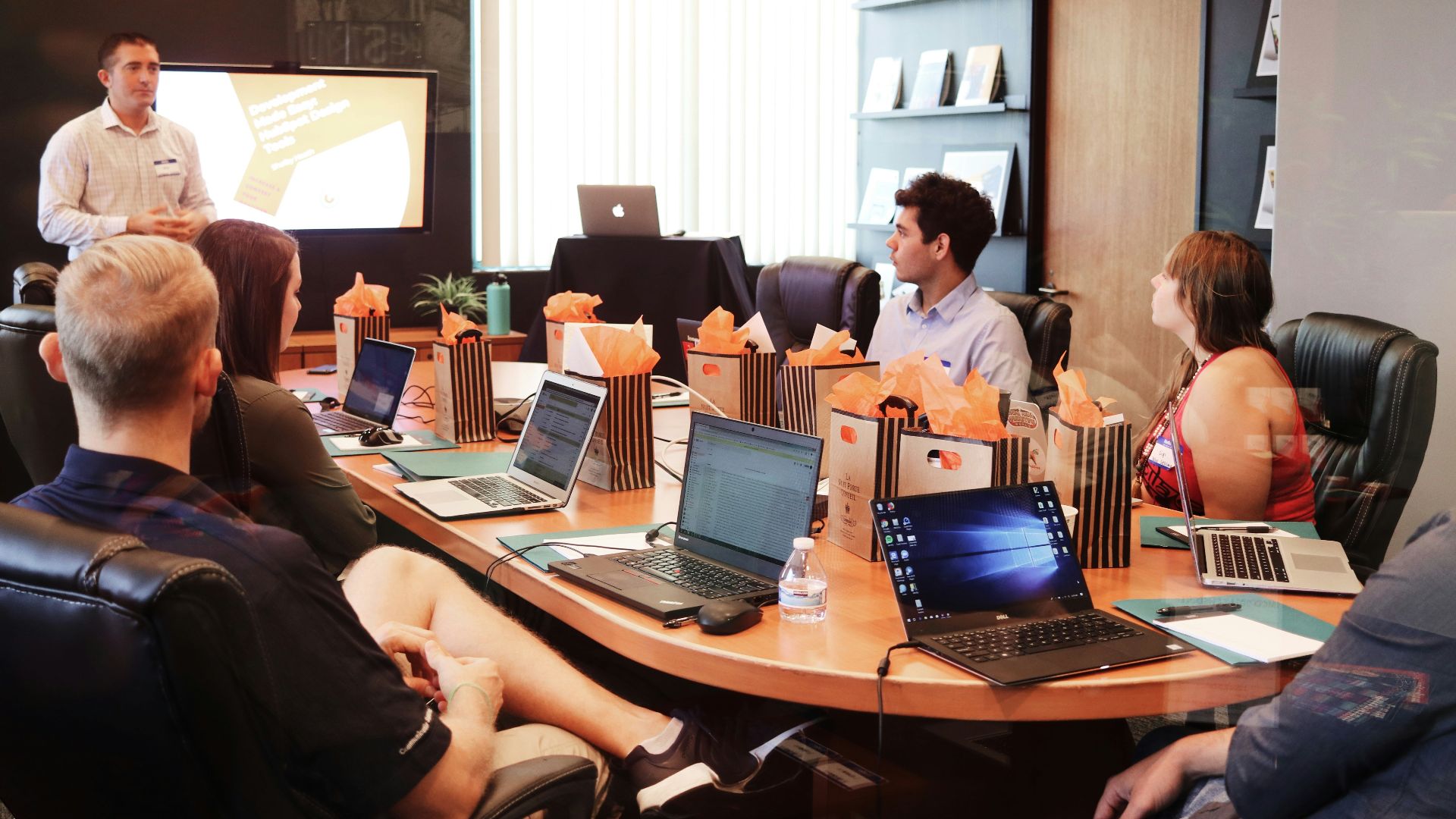 man standing in front of people sitting beside table with laptop computers