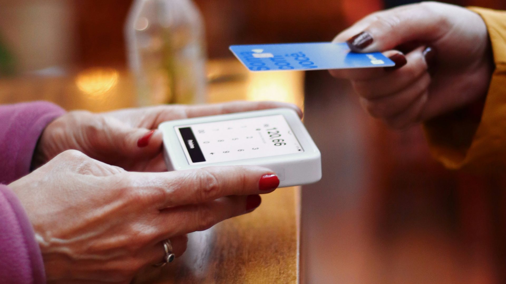 two people exchanging a credit card at a table