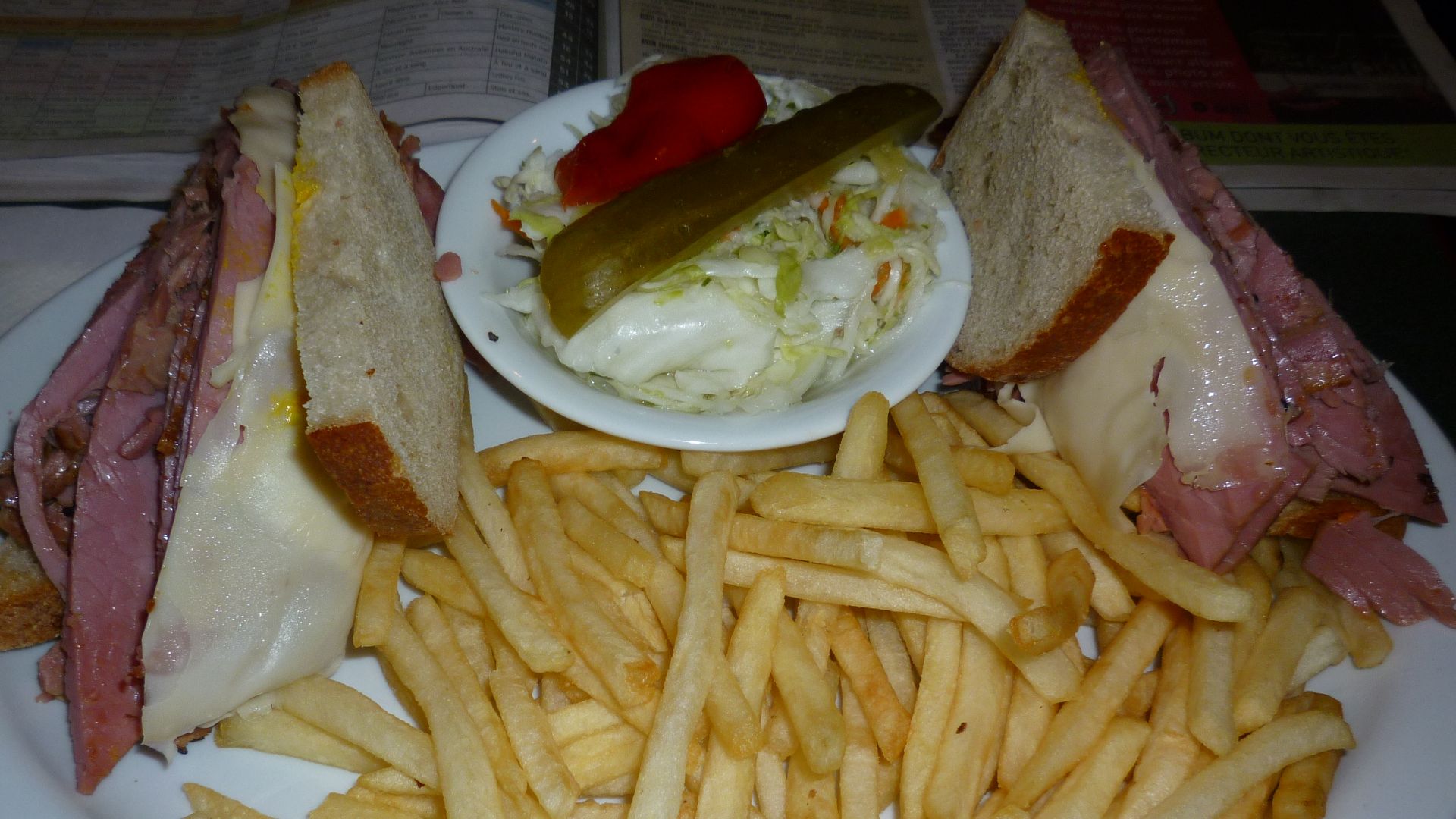 Montreal Style Smoked meat Sandwich on rye bread with swiss cheese and cole slaw and french fries.