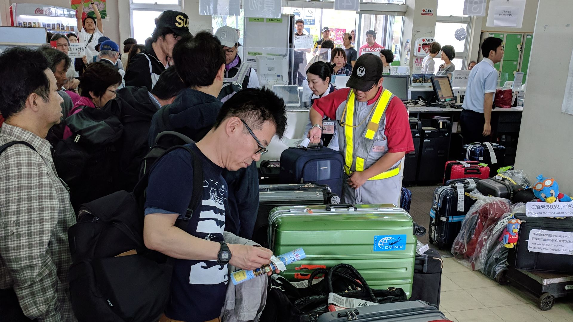 A crowd of people retrieving their luggage at the baggage claim at Yakushima Airport.