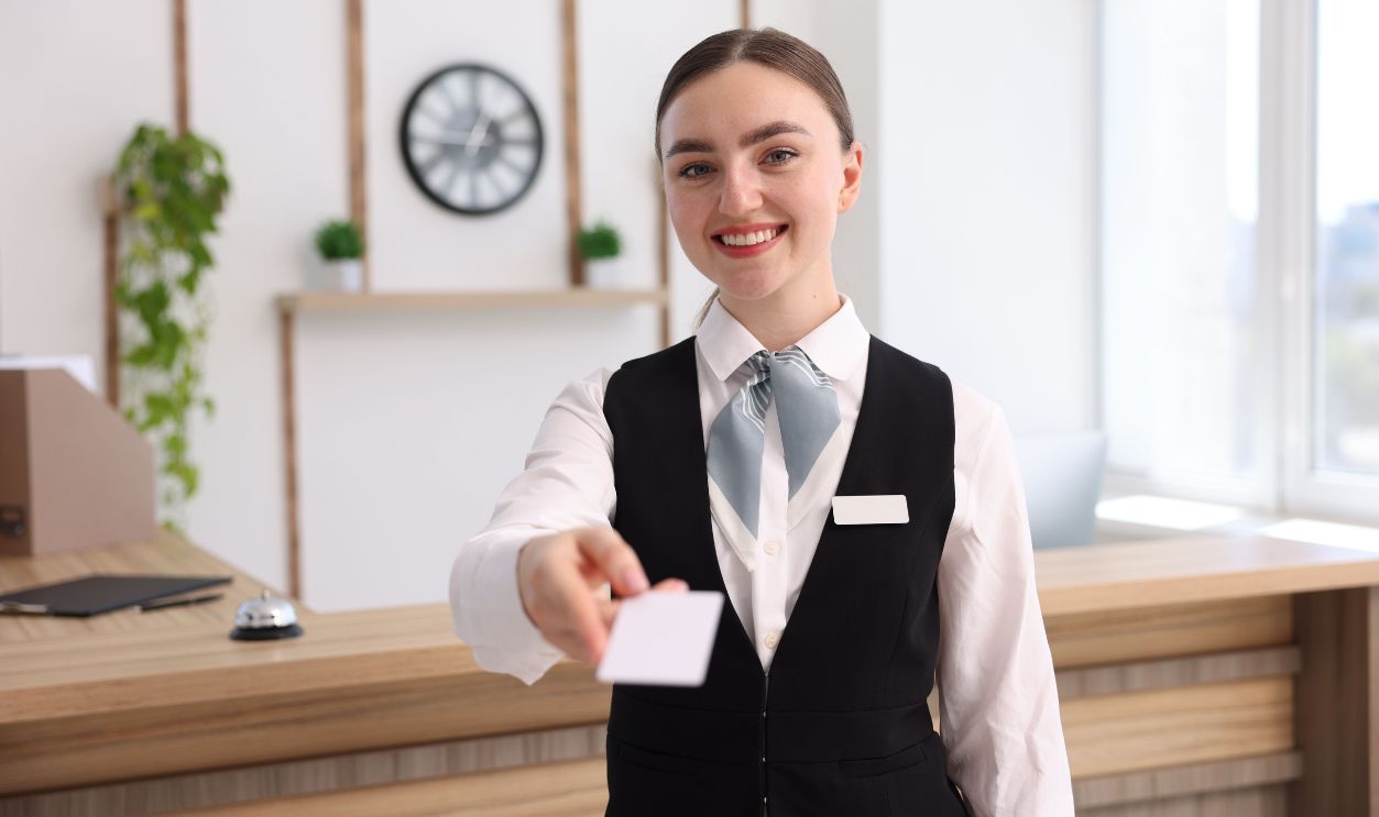 Portrait of smiling receptionist giving hotel key card indoors