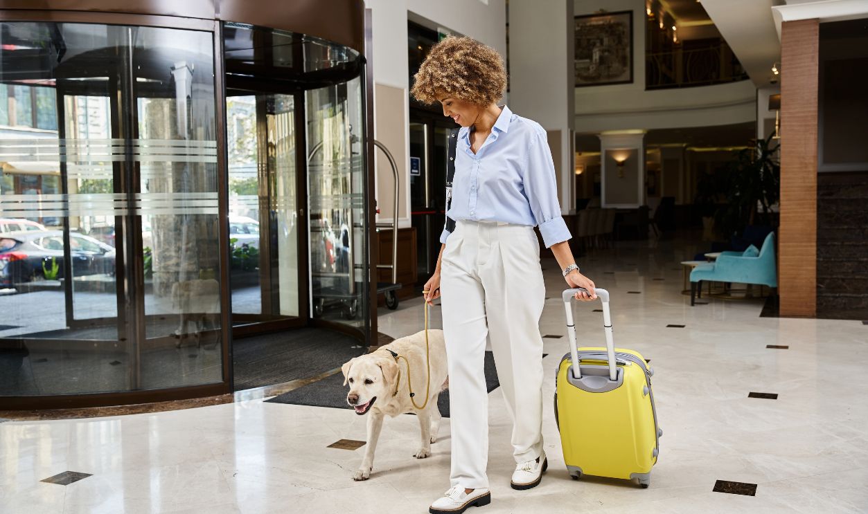 happy tourist with her Labrador in a pet-friendly hotel entrance, african american woman with dog