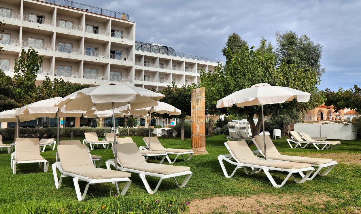 ROSES, SPAIN - OCTOBER 5, 2021: Hotel sunbeds and umbrellas facing the beach in Roses, town in Alt Emporda county in Costa Brava vacation region in Spain.