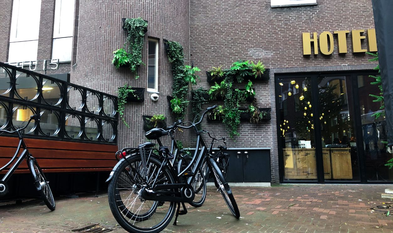 Amsterdam / Netherlands - January 2, 2020: Bike on day light in rainy day. Bicycle on wet street in Amsterdam in rain. Bike over canal. Picturesque town landscape in Netherlands.