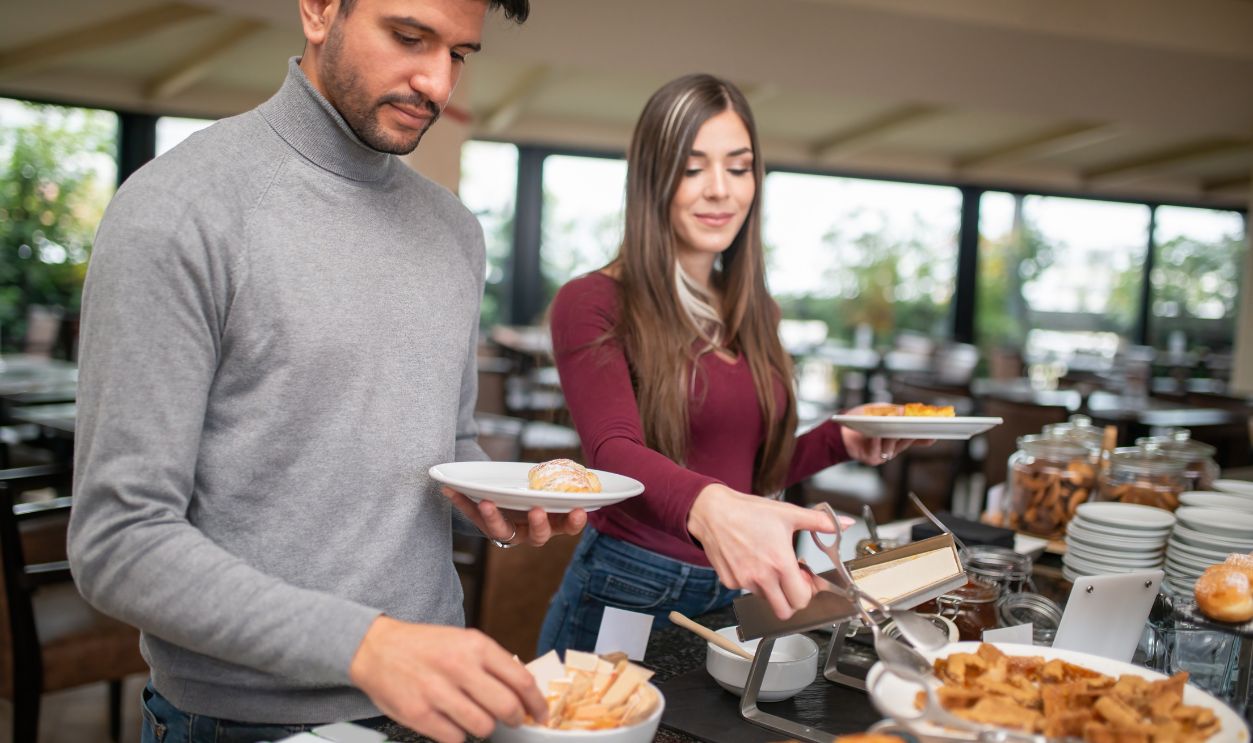 Couple taking sweets, breakfast from buffet in an hotel restaurant