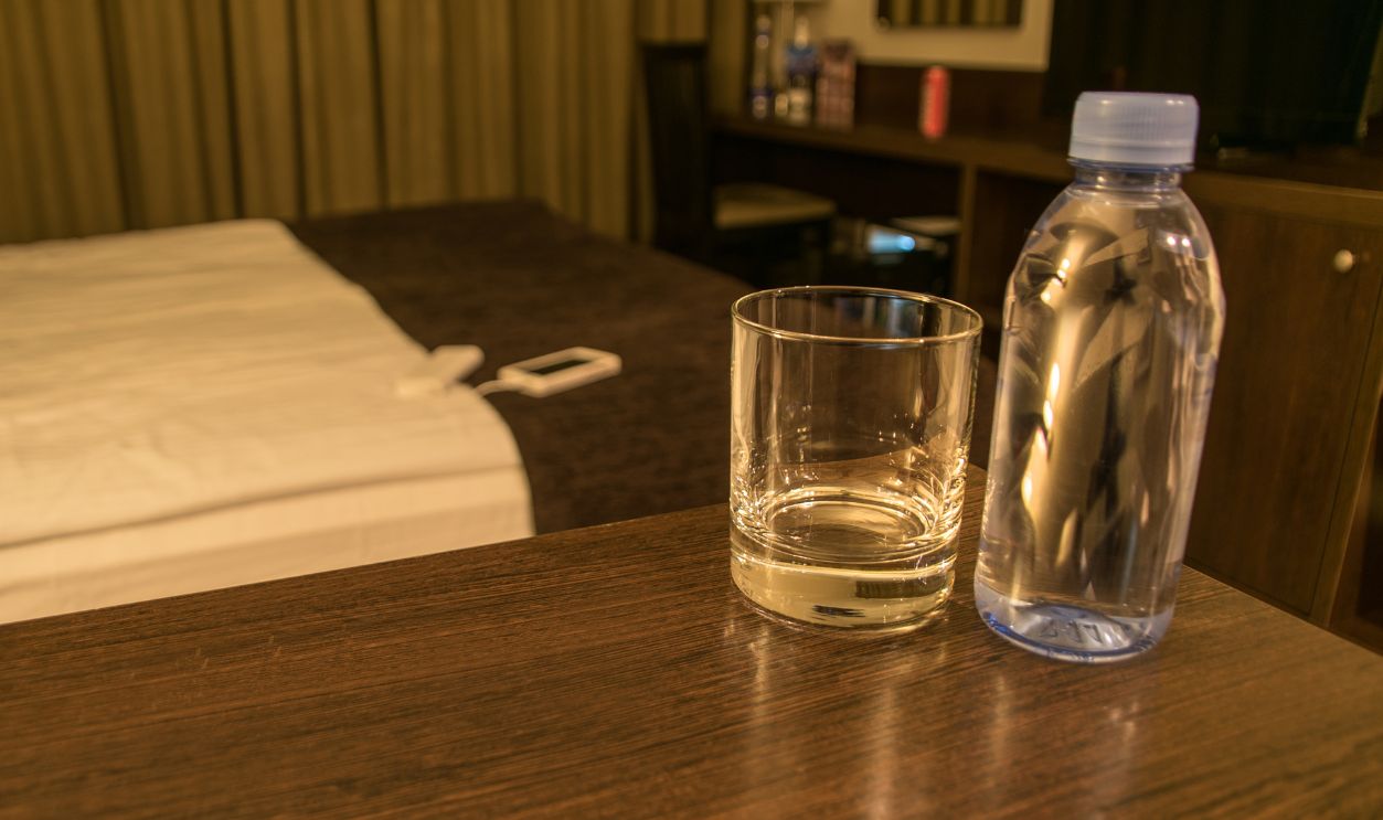 Glass bottle of clean fresh water in the interior of the bedroom in the hotel room, hotel in warm colors.