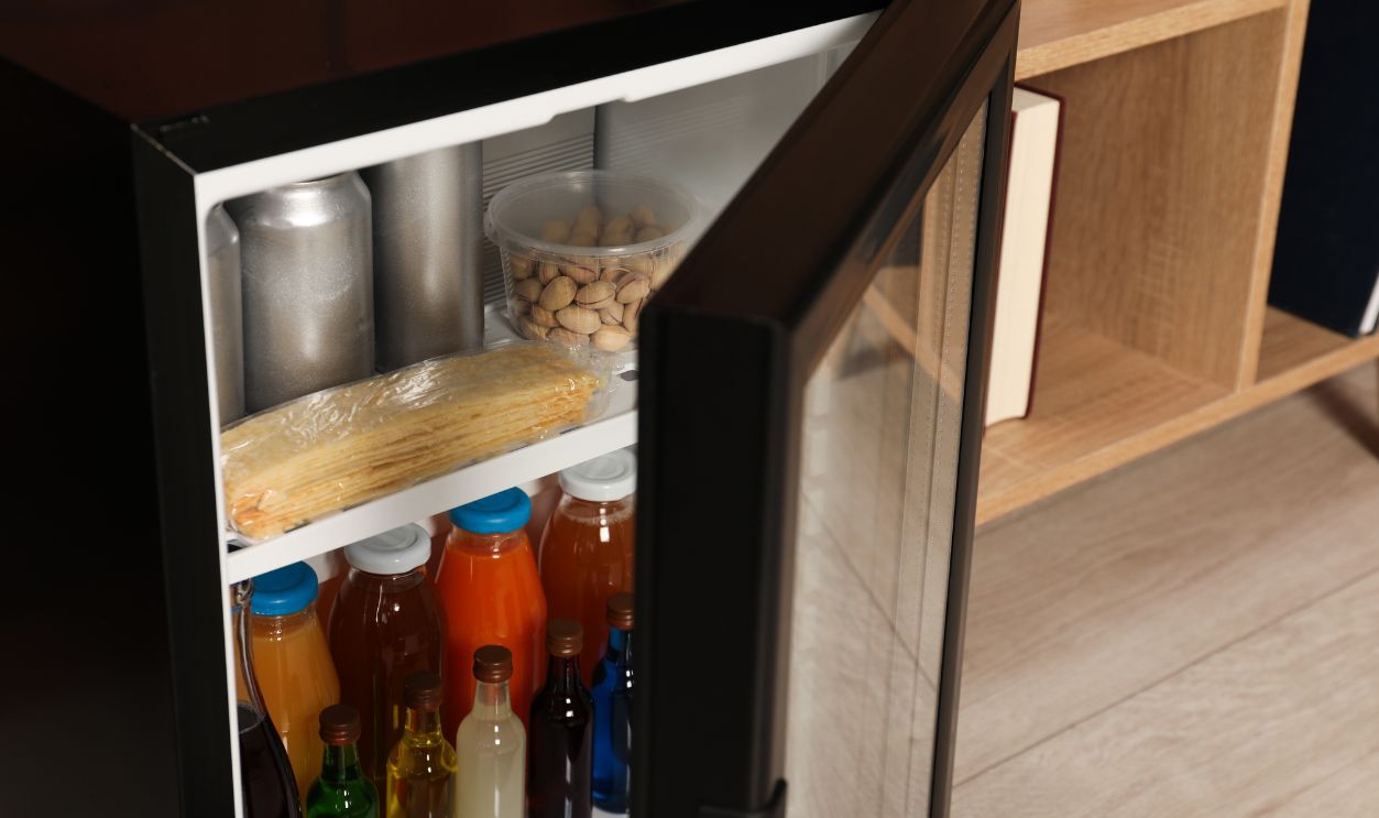 Mini refrigerator with drinks and snacks indoors, closeup