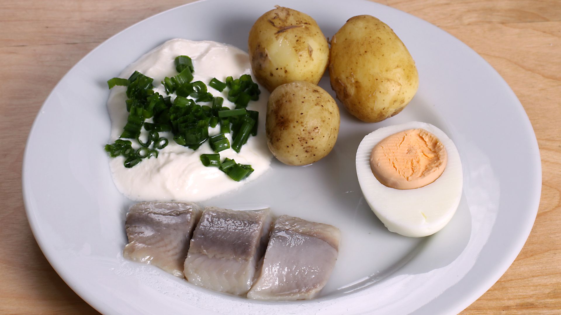 Traditional pickled herring with sourcream and chopped chives, potatoes and an egg half served for the midsummer holliday.