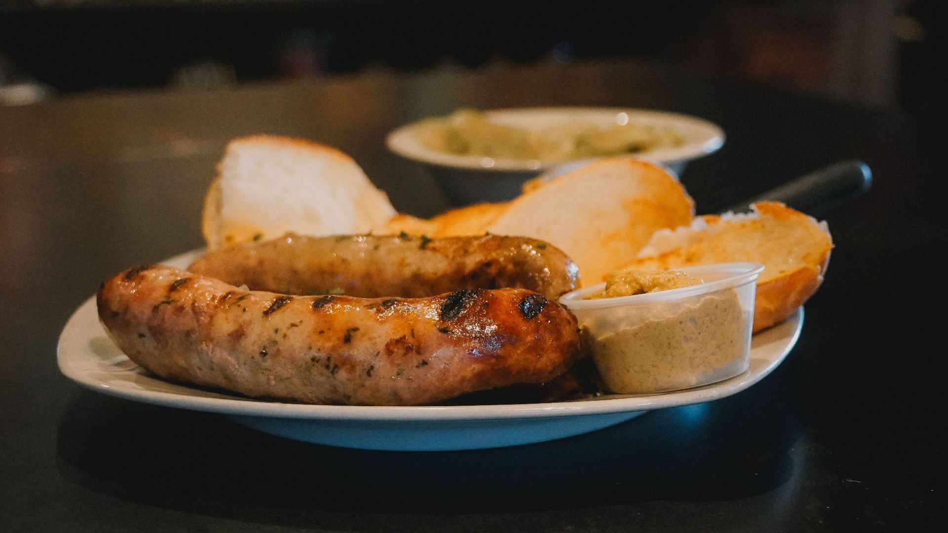 Delicious grilled sausages served with fresh bread and mustard on a white plate.