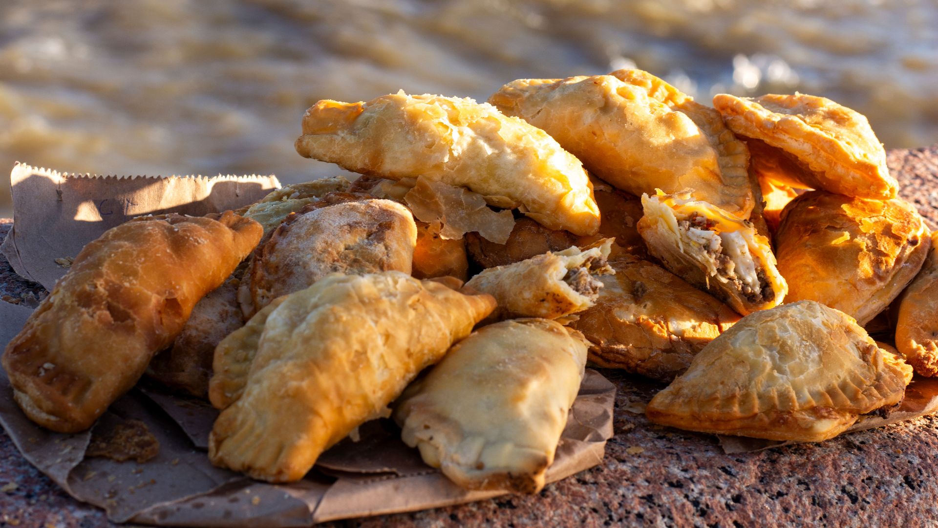 A stack of tasty empanadas on a stone ledge overlooking the sea in Montevideo, Uruguay.