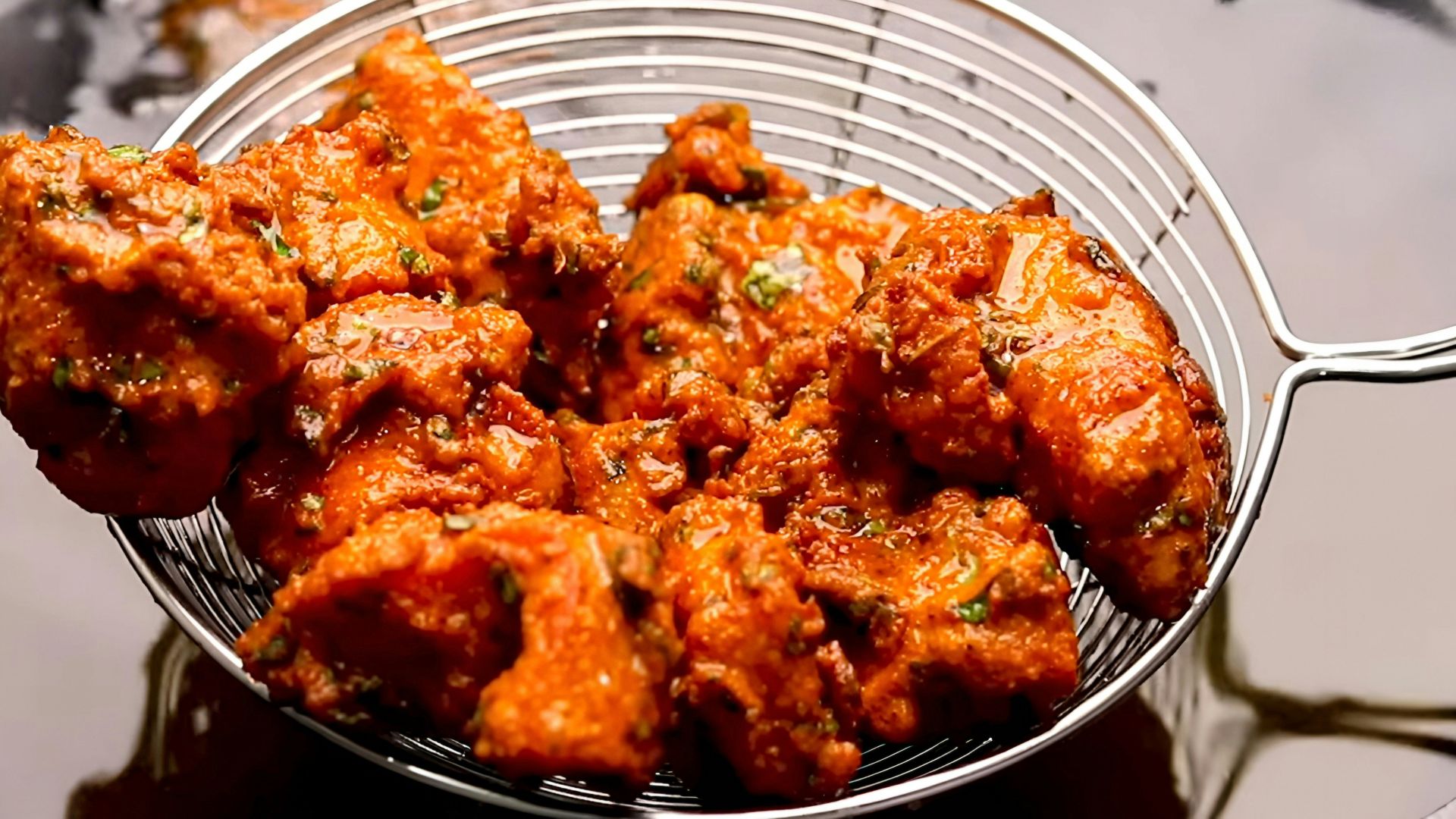 Crispy pakoras being drained in a metal strainer