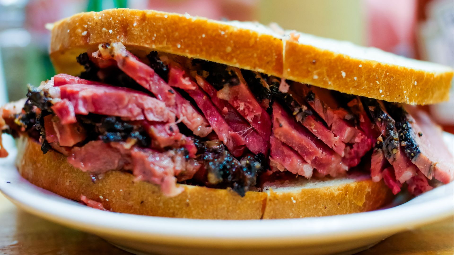 Close-up of a juicy pastrami sandwich with thick slices on white bread.