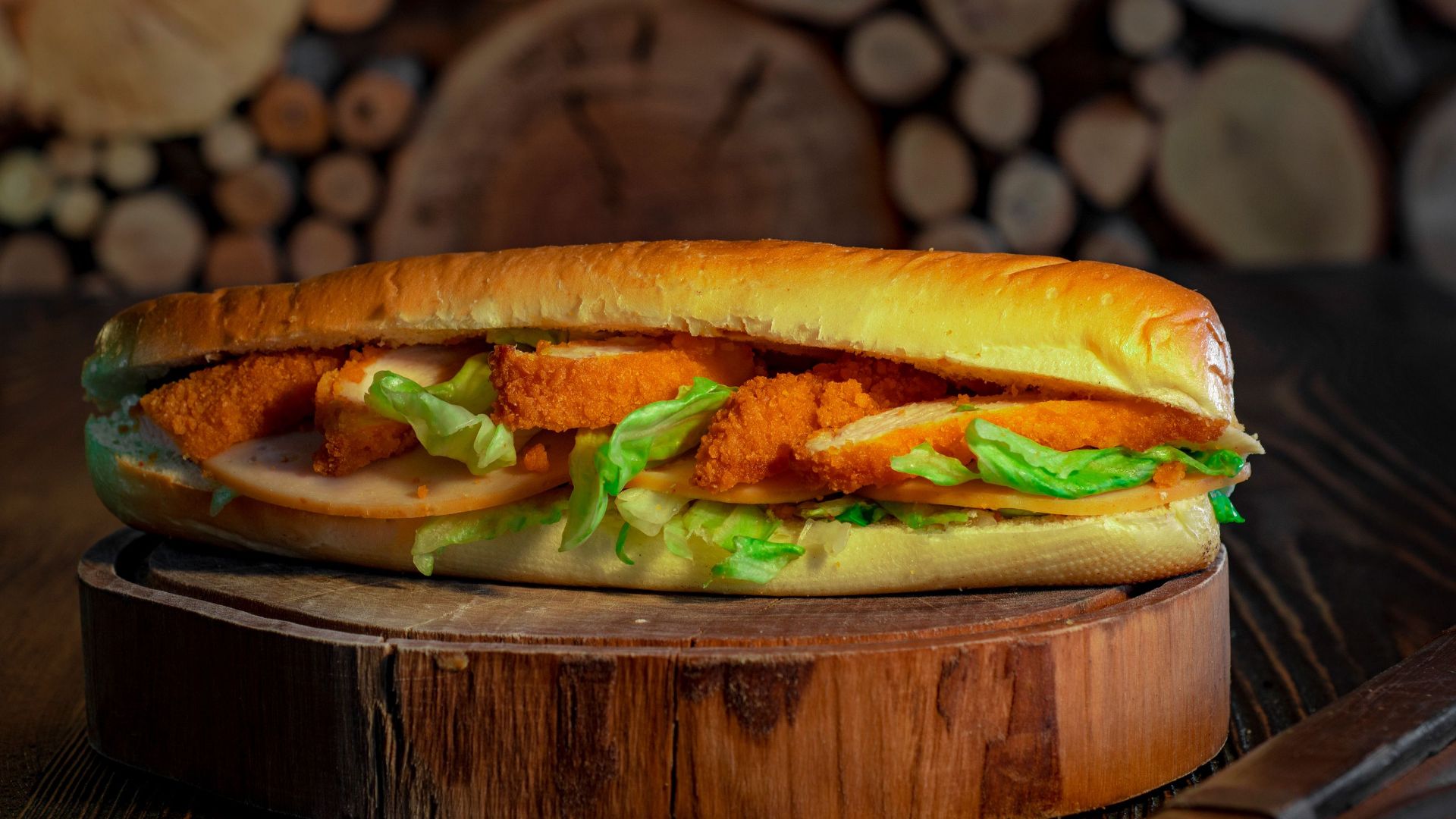 Close-up of a crispy chicken sandwich with fresh lettuce on a wooden board, perfect for a tasty meal.