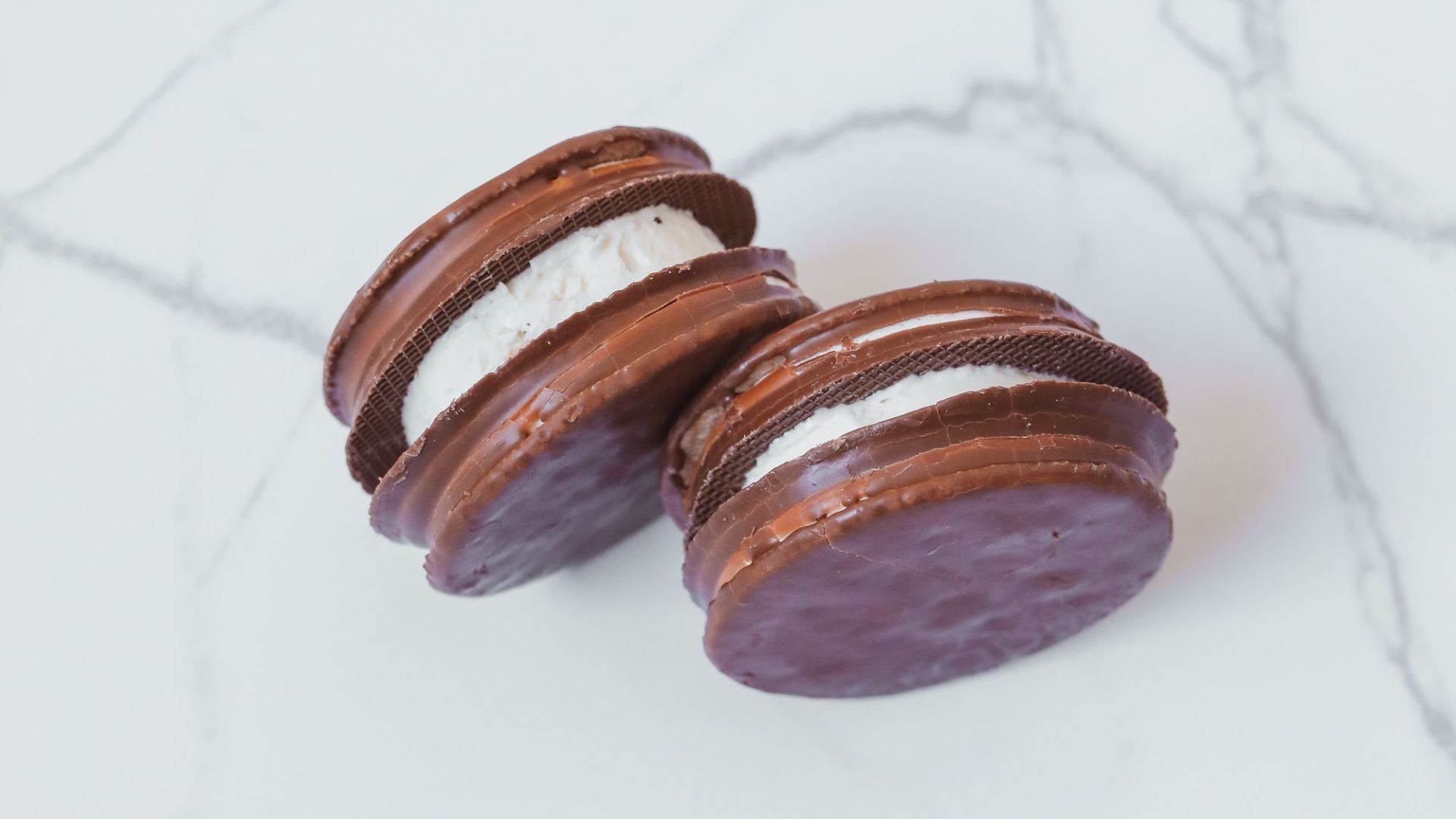 Delicious chocolate macarons with creamy filling on a marble background. Perfect for dessert and confectionery visuals.