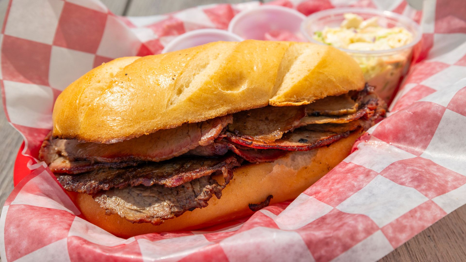 Mouthwatering brisket sandwich served in a red checkered basket with coleslaw on the side.