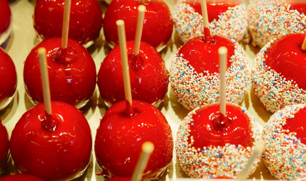 Bright red candy apples with colorful sprinkles on display, perfect for desserts
