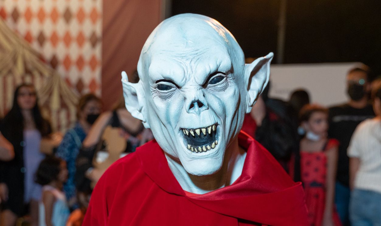 Frightening goblin in a red robe at a lively Halloween party