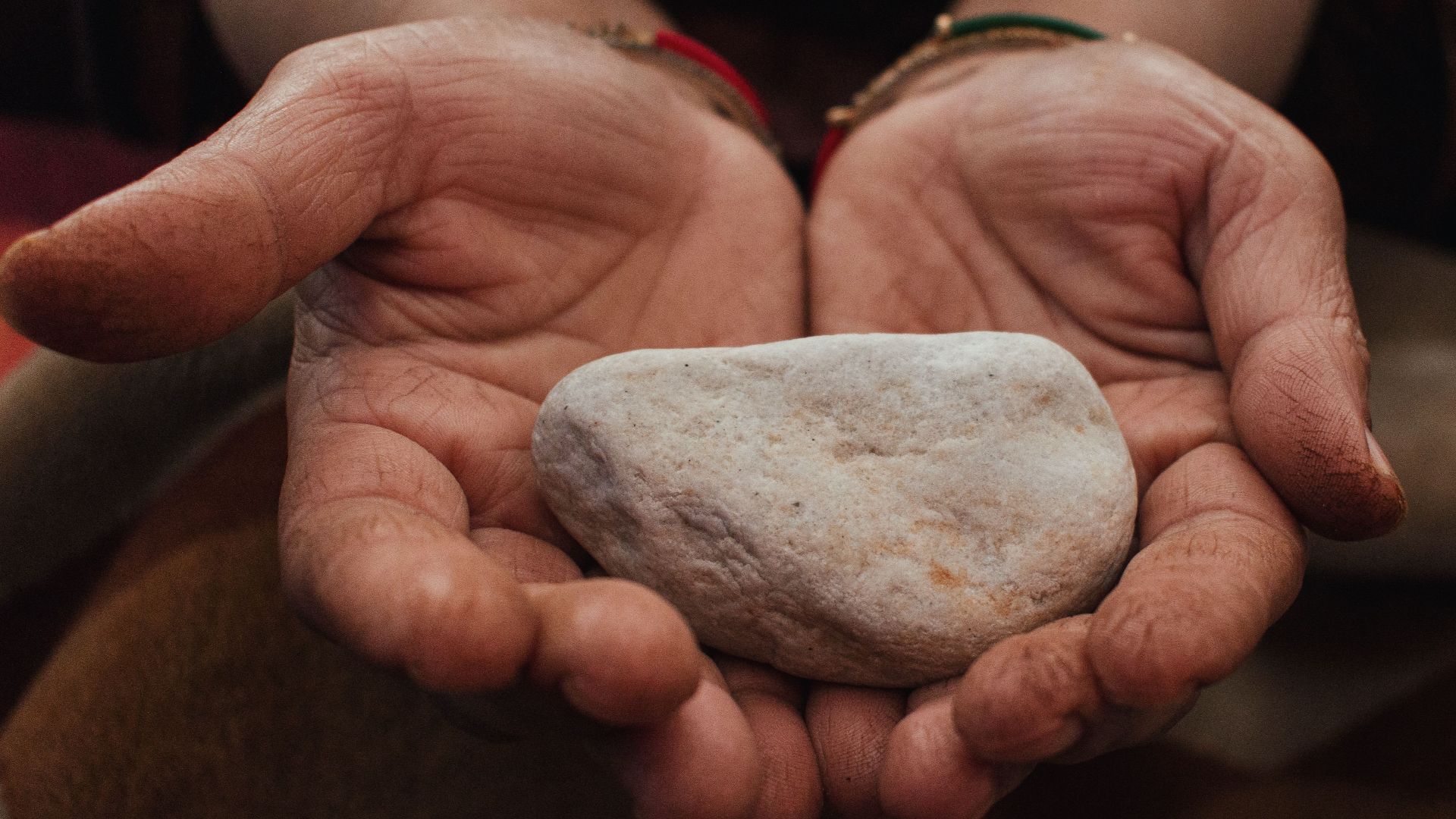 A close-up shot of hands gently cradling a smooth white stone, conveying serenity and care.