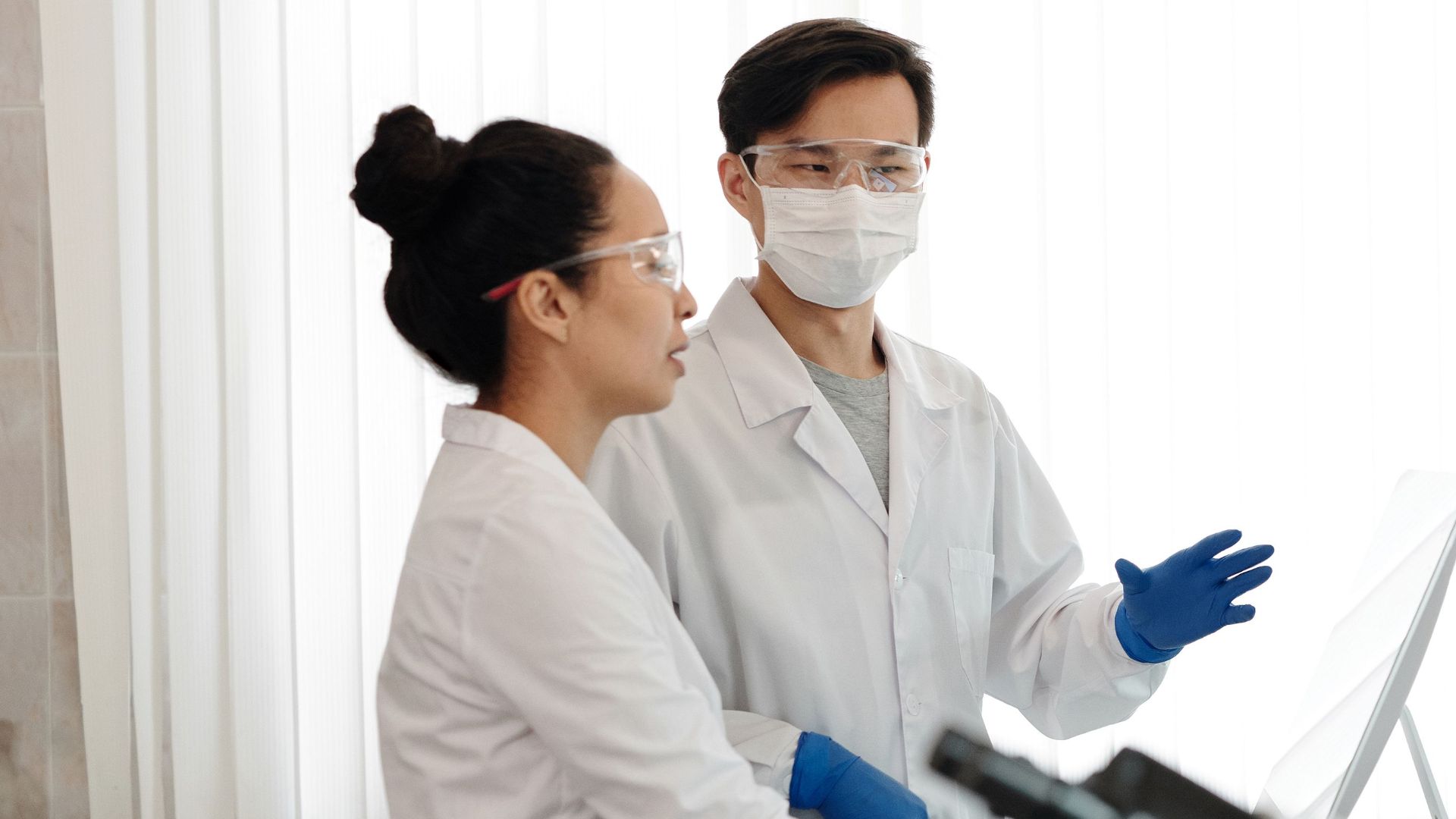 Scientists in a lab discussing experiments and wearing safety gear.