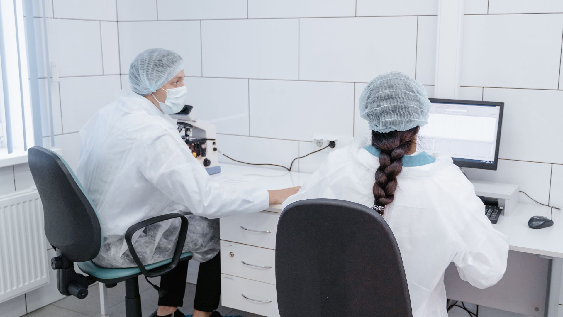 Two scientists working together in a sterile lab environment.