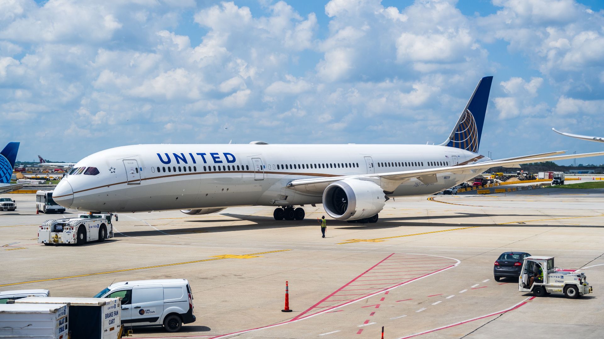 United Airlines Boeing 787 Dreamliner parked at an airport terminal on a sunny day.