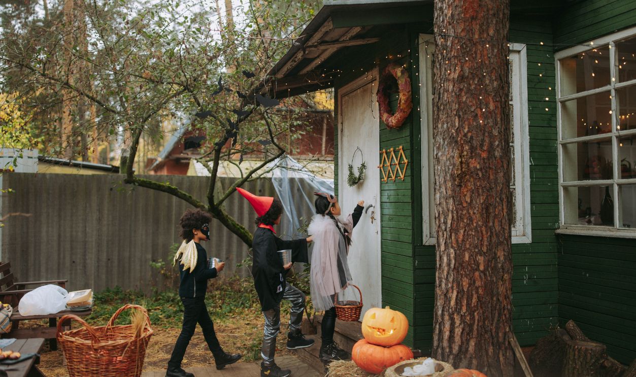 Group of kids in Halloween costumes trick or treating at a house
