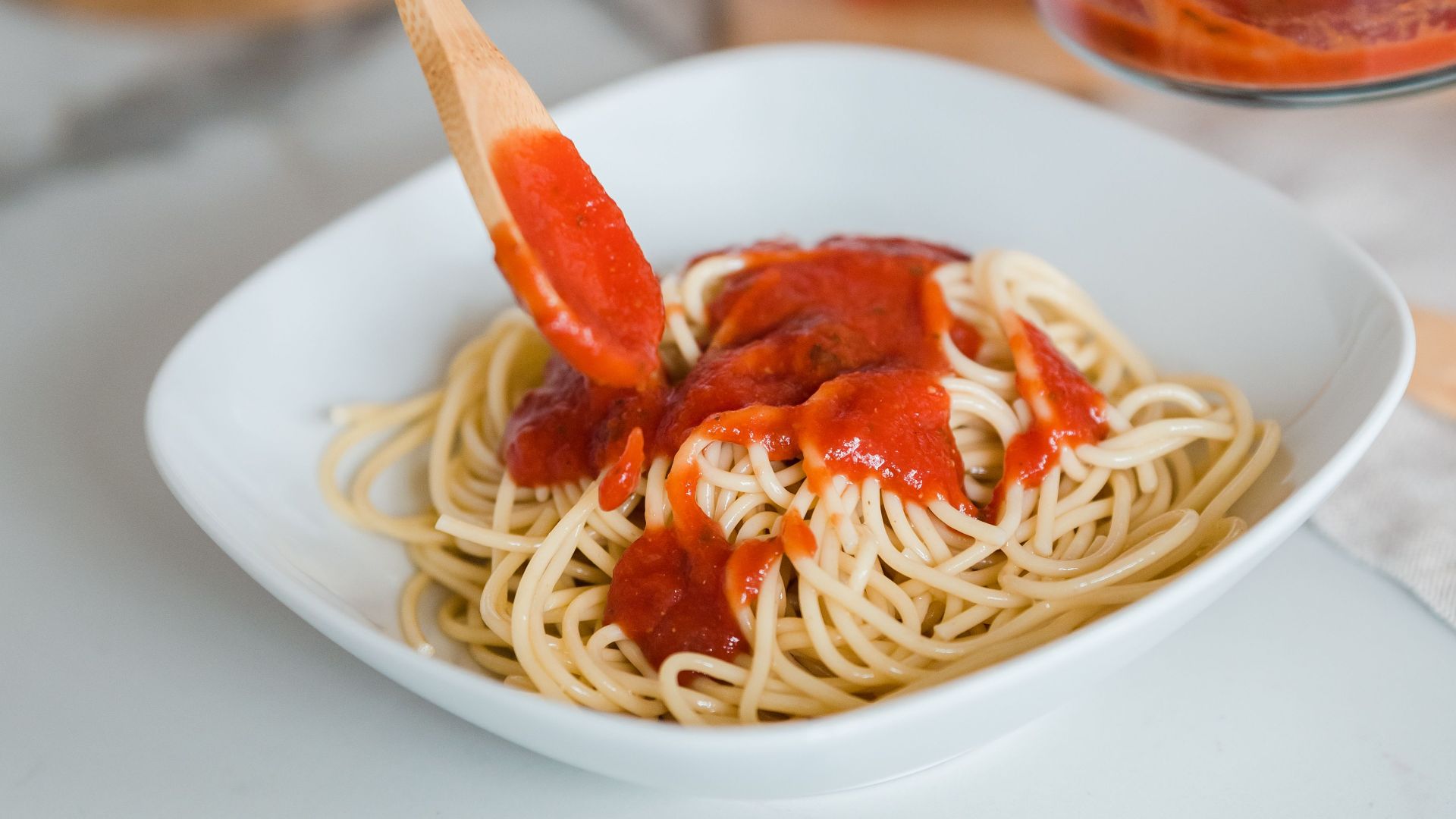 Close-up of spaghetti being served with fresh tomato sauce, perfect for culinary themes.