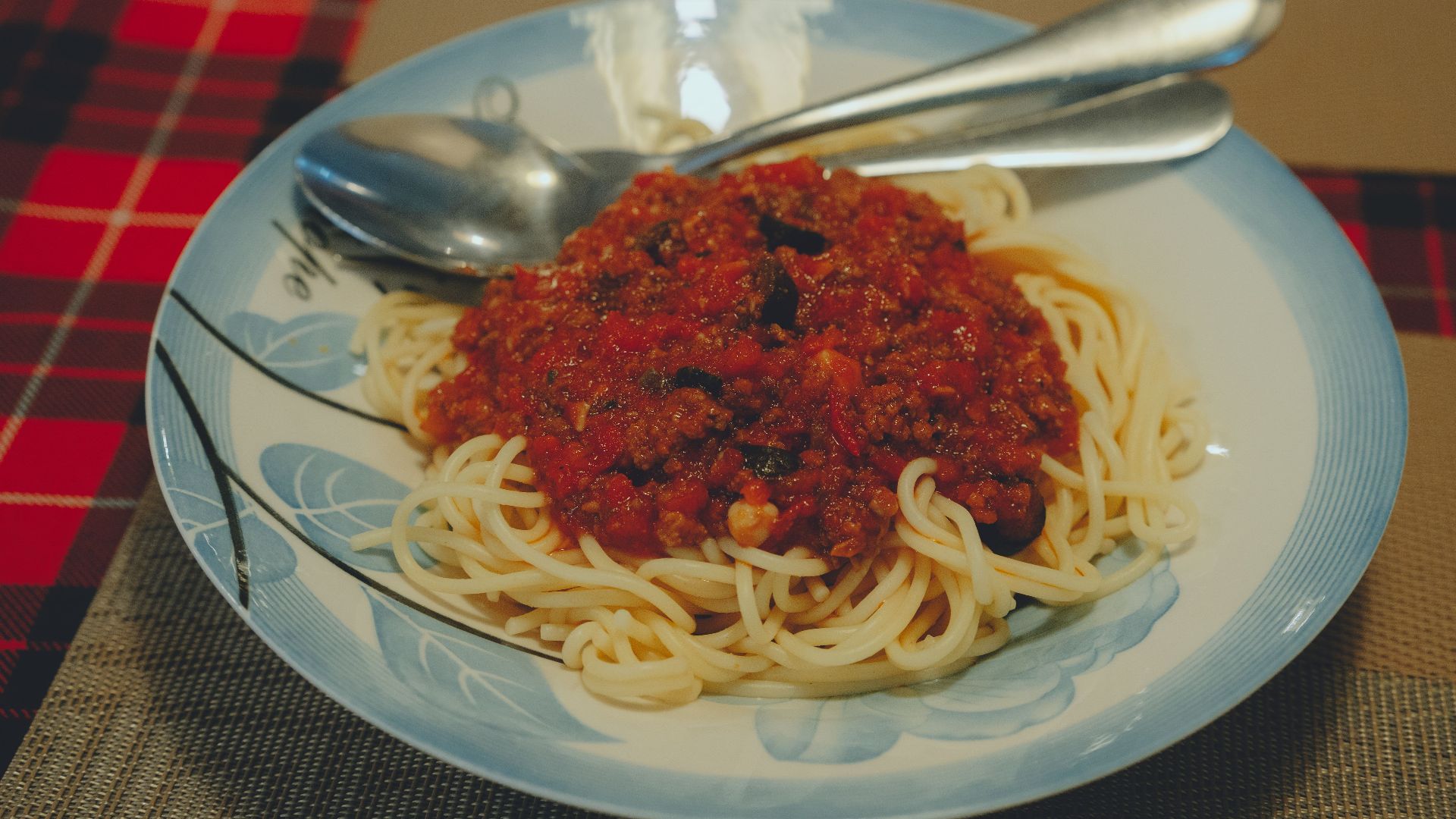 A plate of spaghetti topped with a rich meat and tomato sauce on a dining table in Ho Chi Minh City, Vietnam.