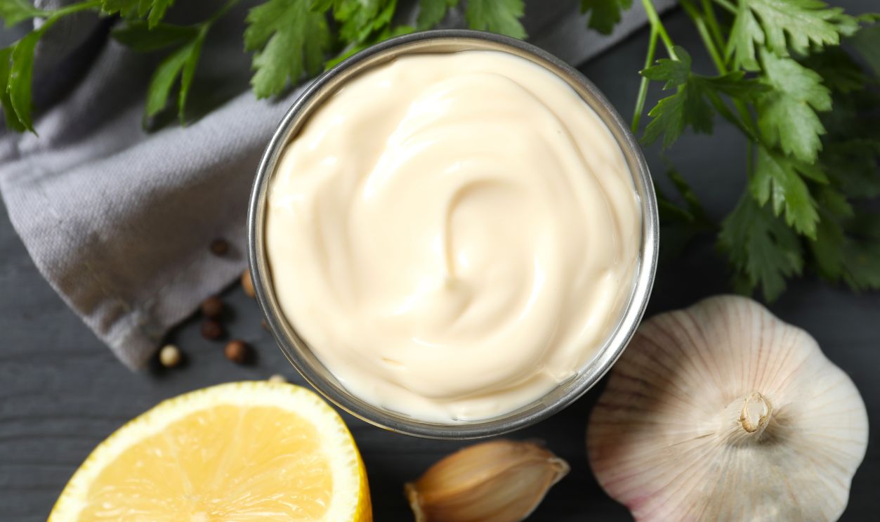 Bowl with mayonnaise and ingredients for cooking on wooden background