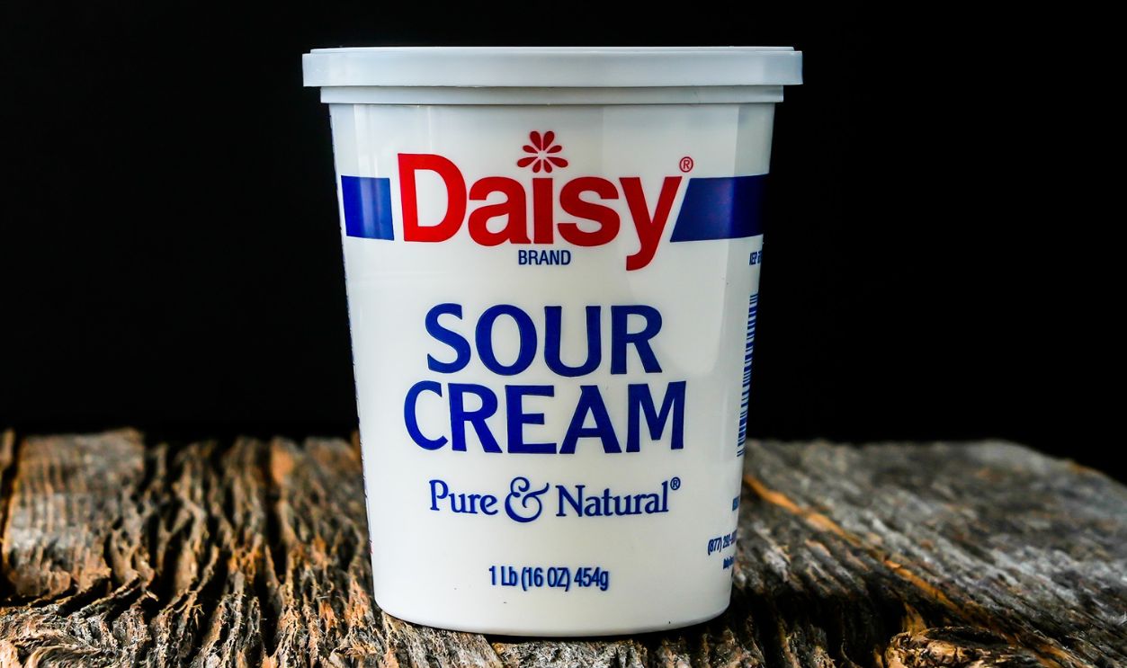 NORWALK, CT, USA - MAY 1, 2022:  Daisy sour cream on rustic wooden table with black background