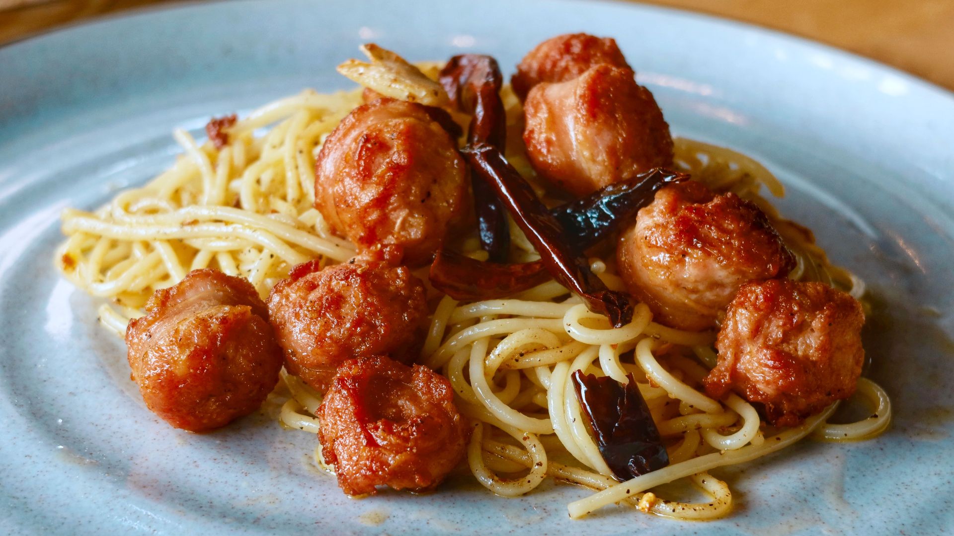 Delicious spaghetti with meatballs and dried chilies on a plate, ideal for Italian cuisine lovers.