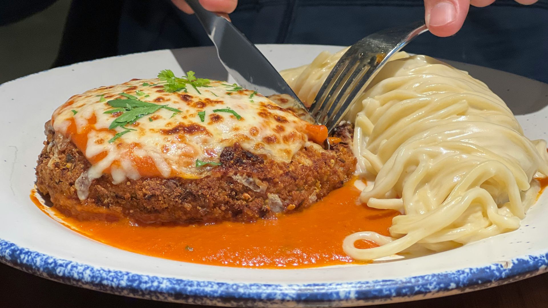 a person cutting a piece of meat with a knife and fork