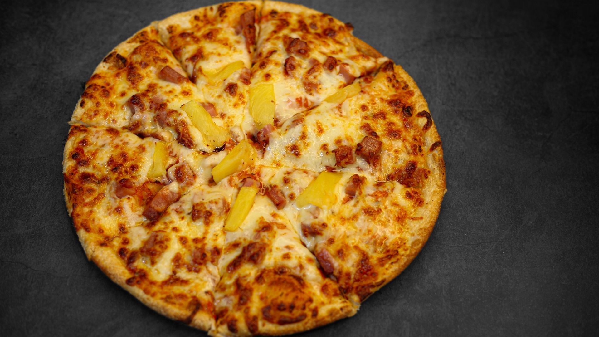 A whole pizza with pineapple and meat toppings