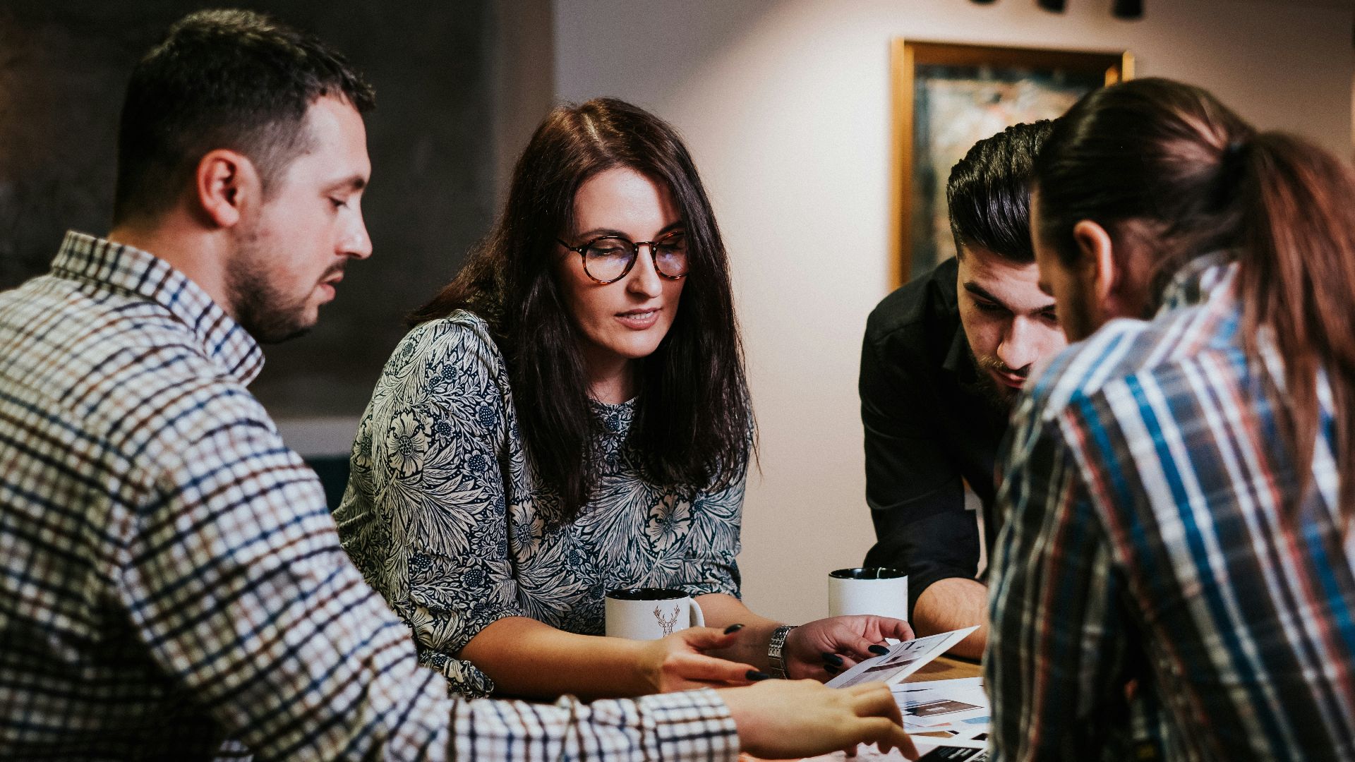 Four people reviewing documents at a wooden table in a workspace