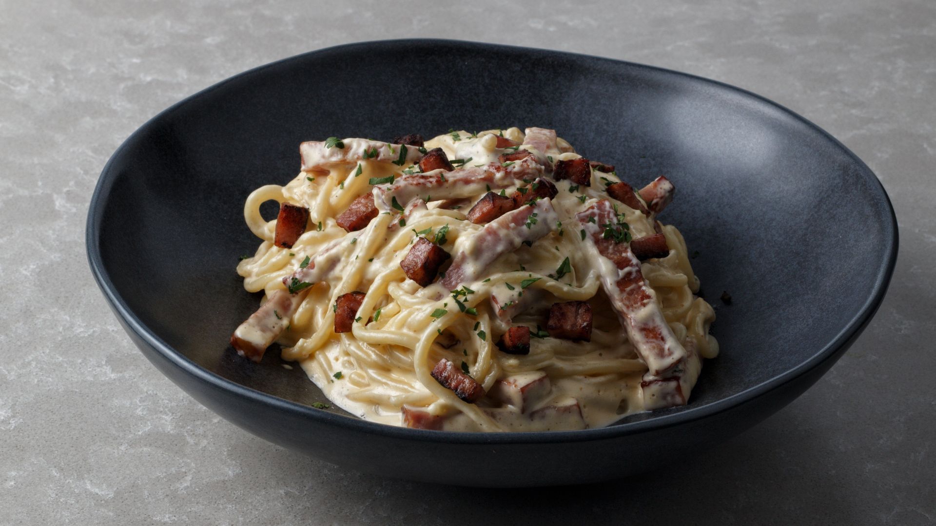 Mouth-watering spaghetti carbonara with creamy sauce and crispy bacon bits served in a bowl.