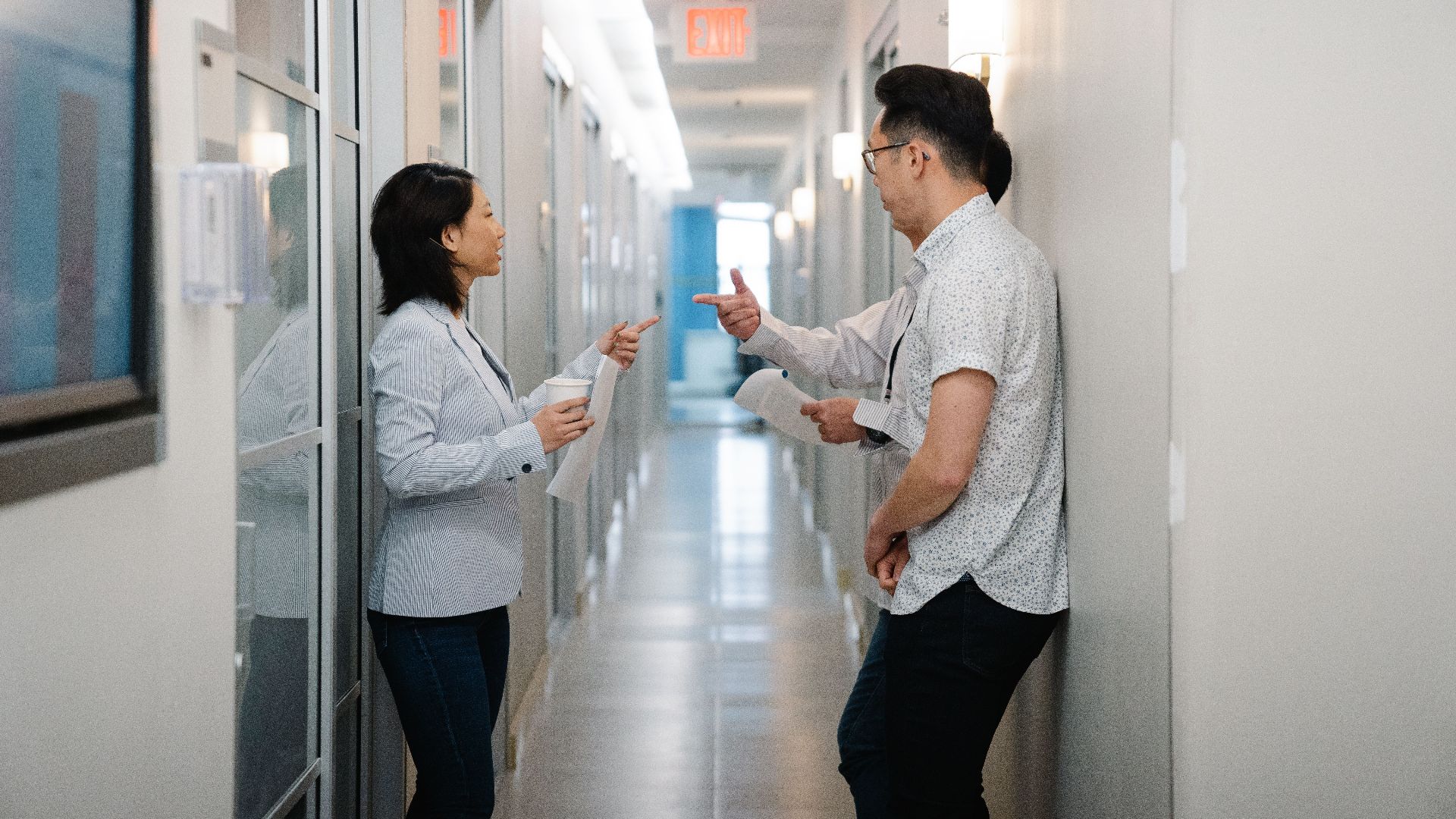 Business professionals discussing teamwork in a modern office hallway.