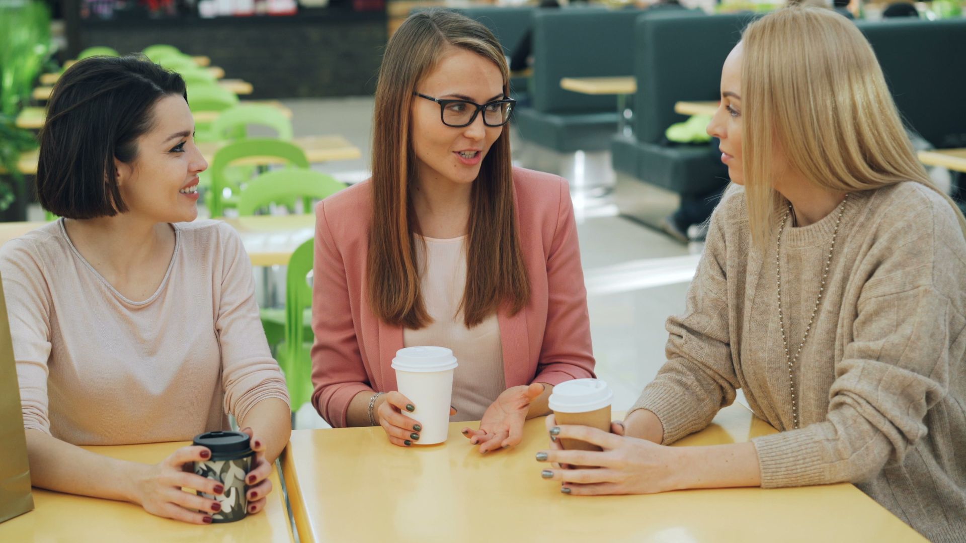 Casual conversation among friends in a modern mall cafe setting.