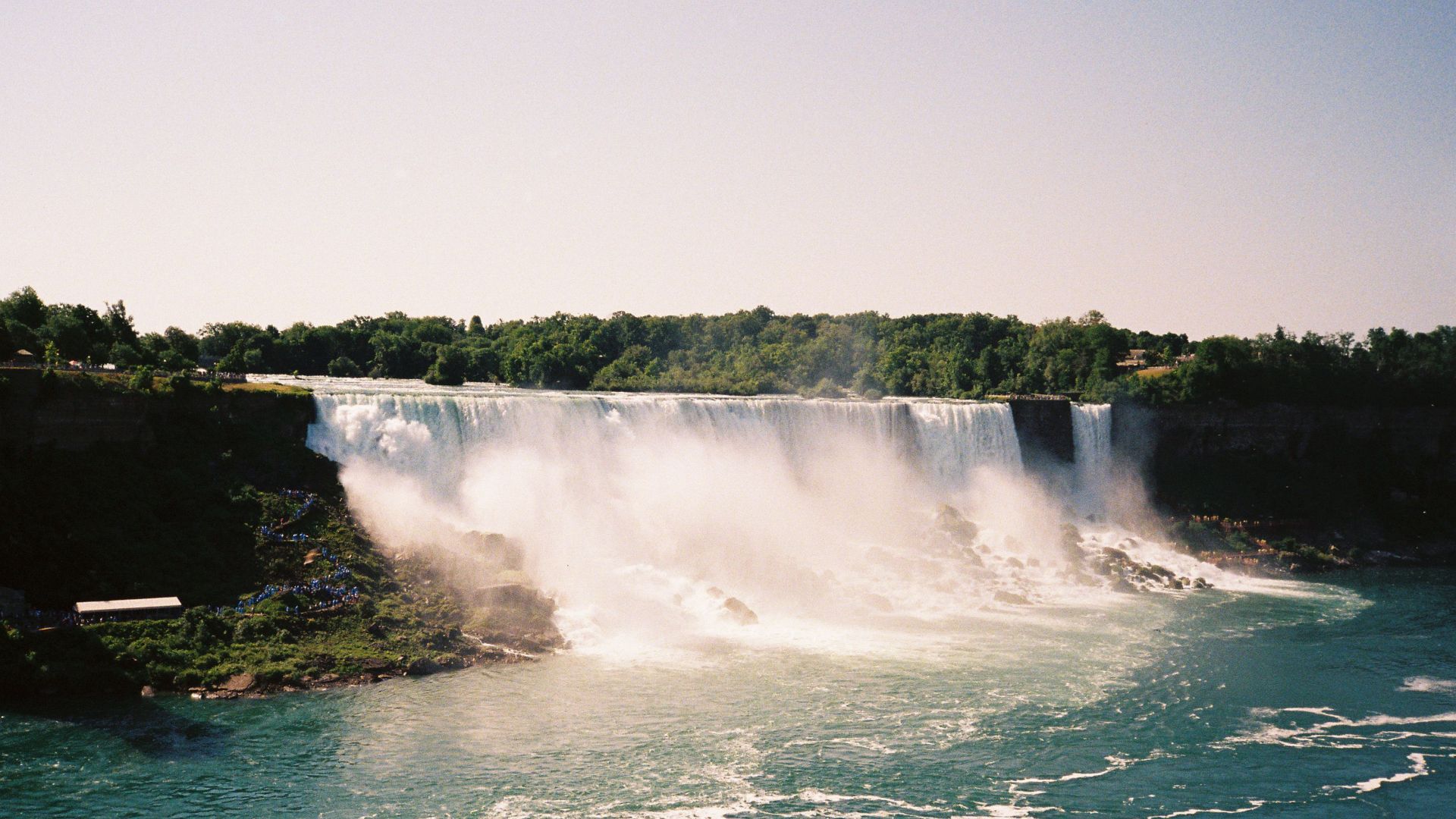Dramatic photo of the majestic Niagara Falls with lush green surroundings.