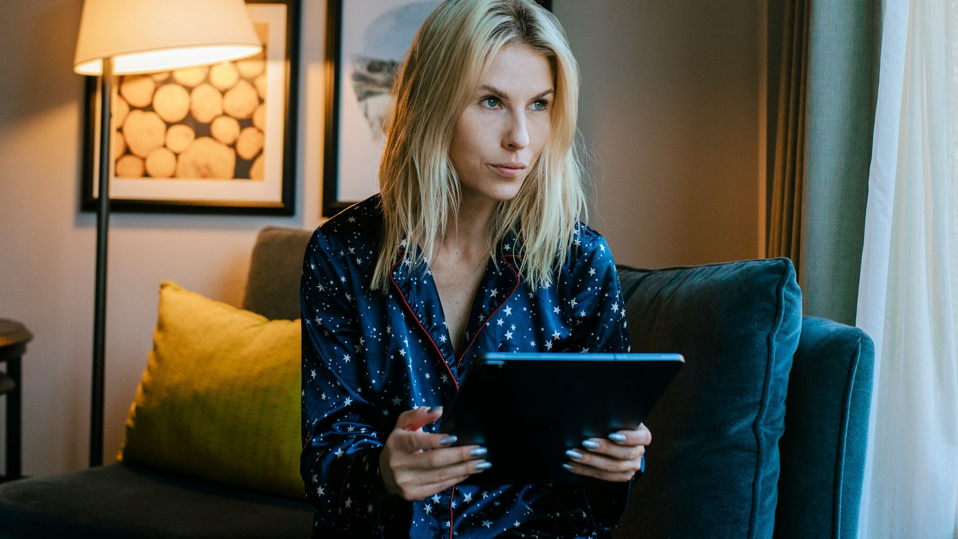 a woman sitting on a couch looking at a tablet