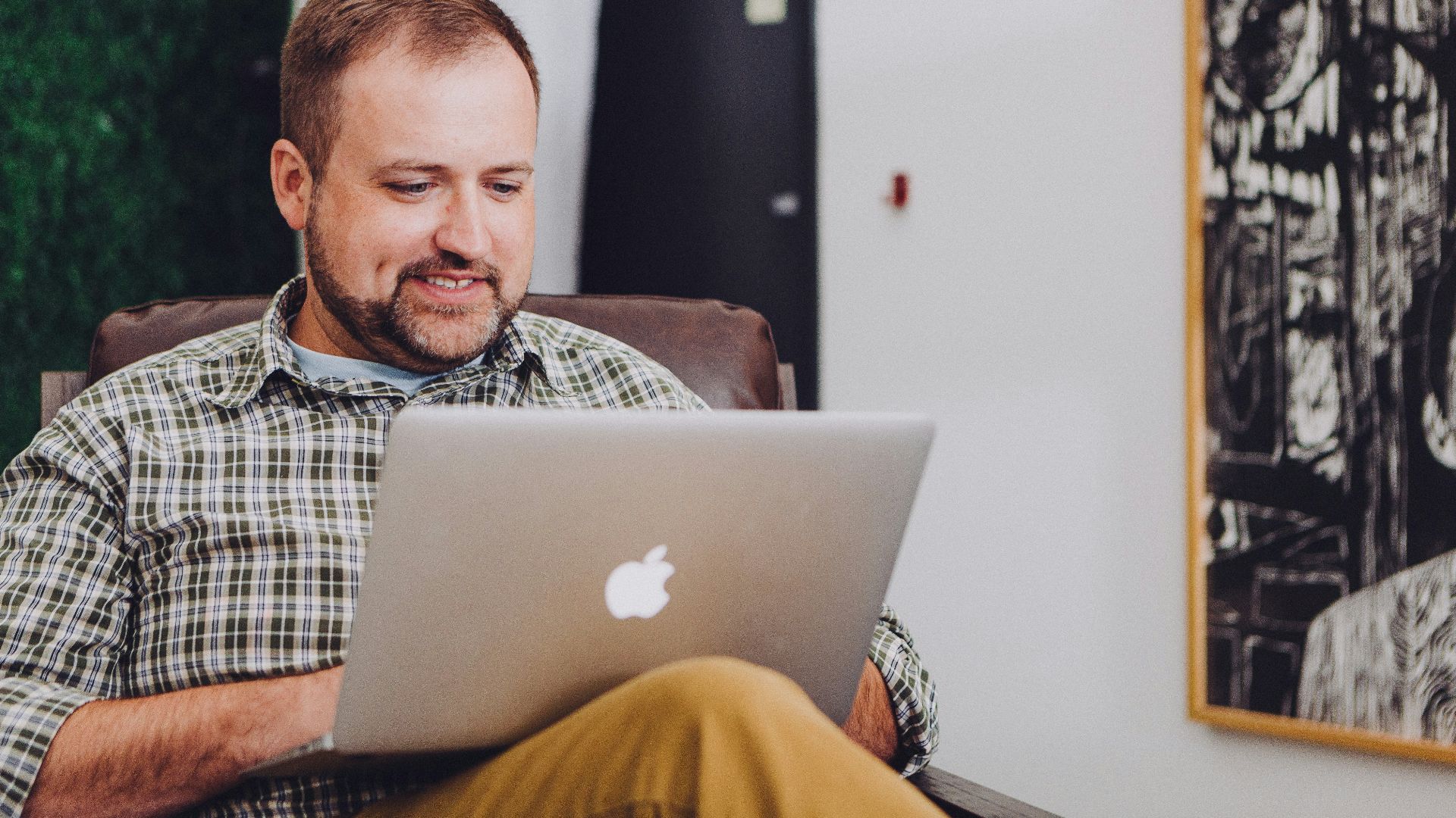 man smiling and using MacBook