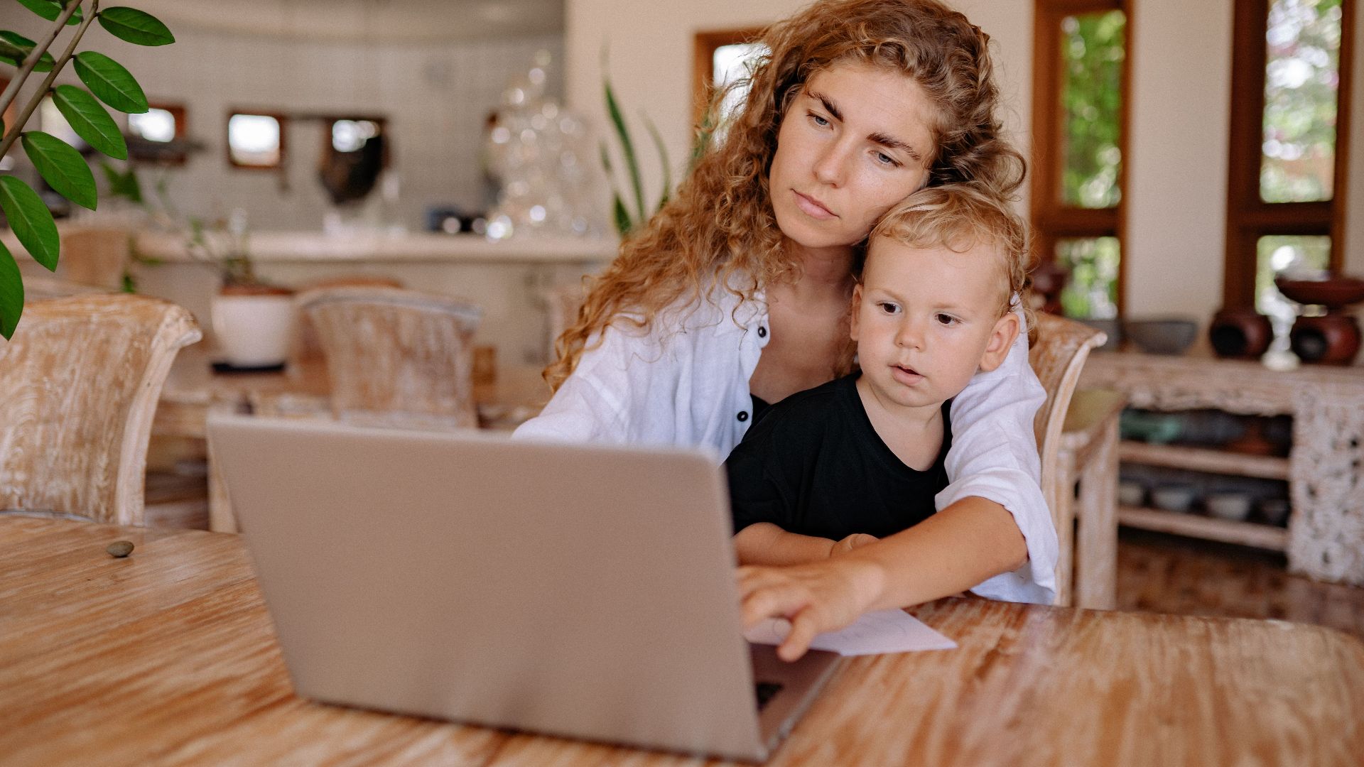 Mother and child using a laptop at home, working and bonding in a cozy environment.