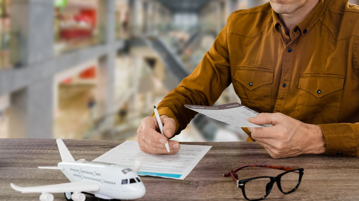 Shutterstock-2174570605, Young male traveler signing travel insurance policy booklet in airport