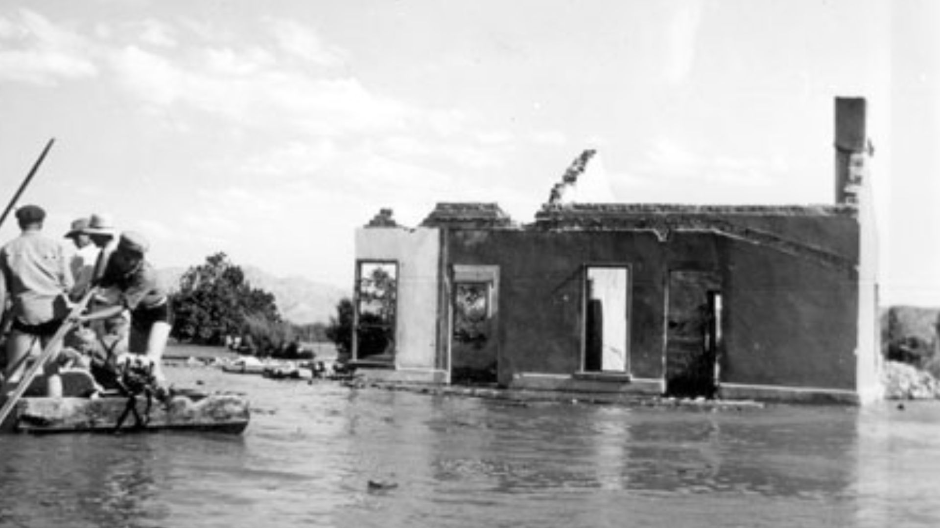 A salvage crew rafts through the town of St. Thomas near the ruins of a building as Lake Mead begins to submerge it in June 1938.