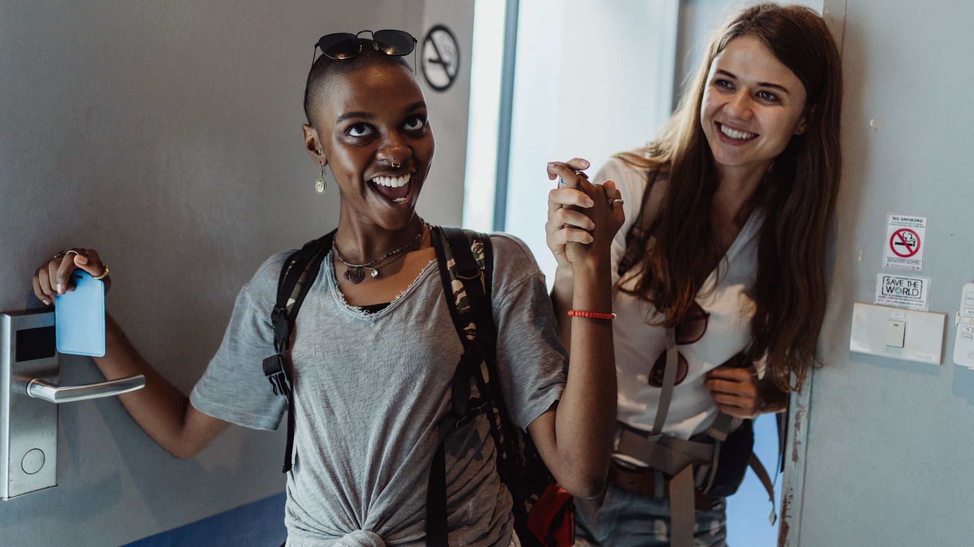 Two cheerful women entering a modern room, capturing moments of fun and friendship.