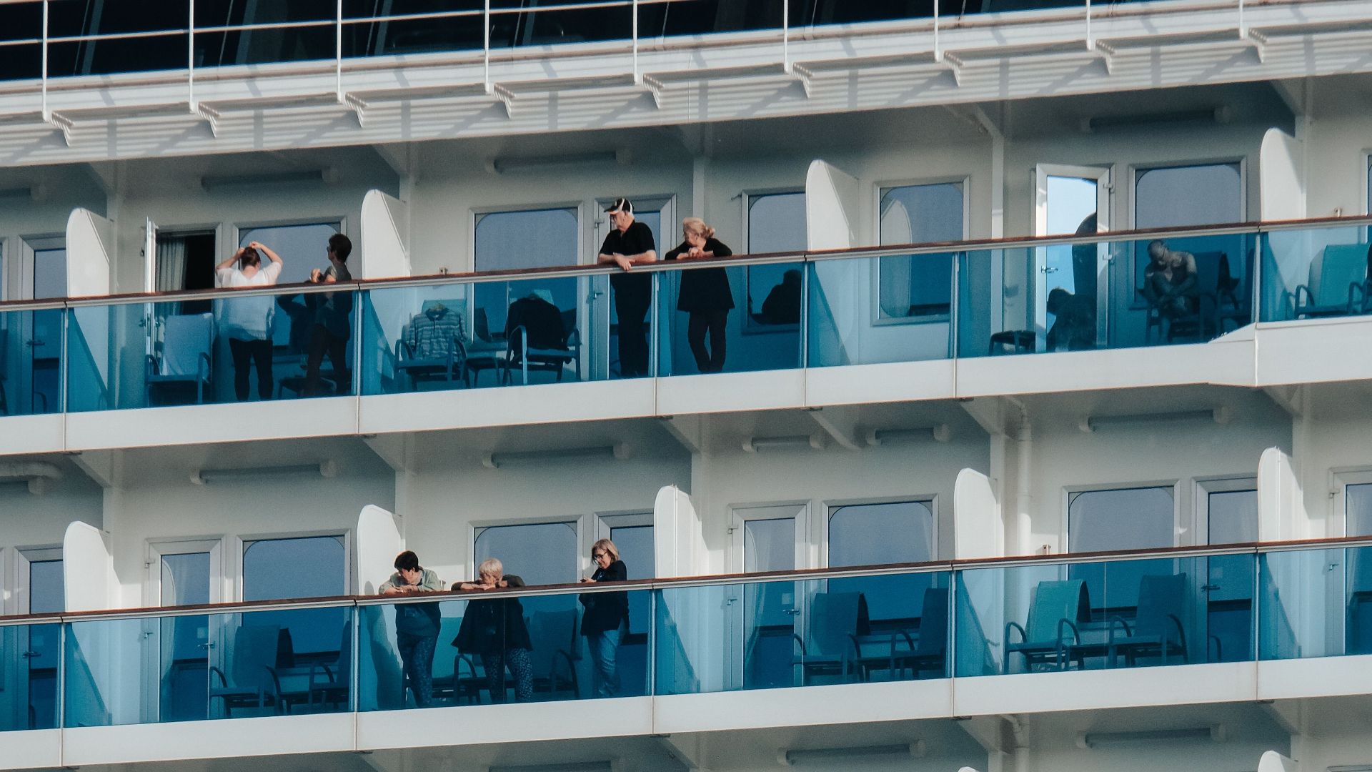Close-up of cruise ship balconies with people enjoying the view, showcasing modern luxury travel.