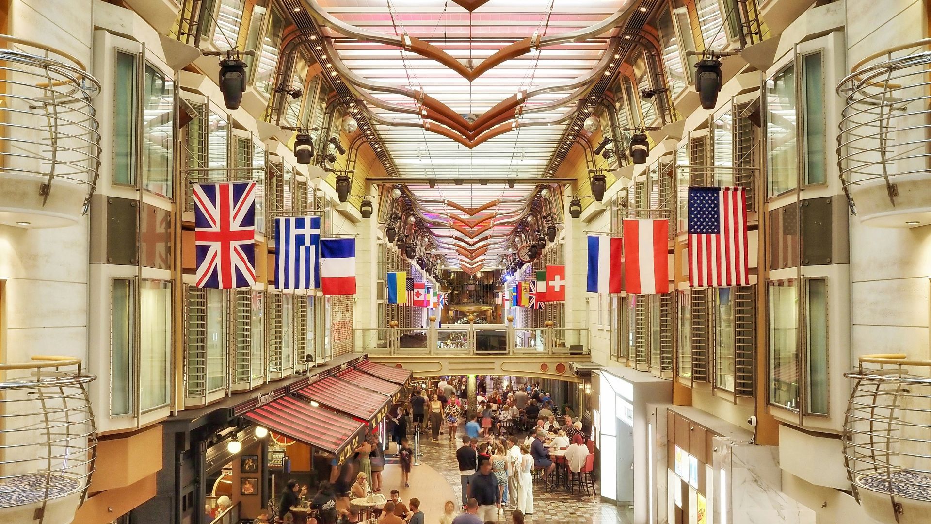 Vibrant cruise ship promenade featuring shops, restaurants, and international flags